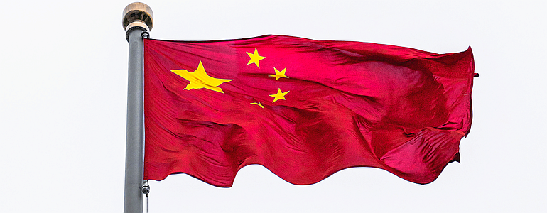 a PRC flag flies in a stiff breeze